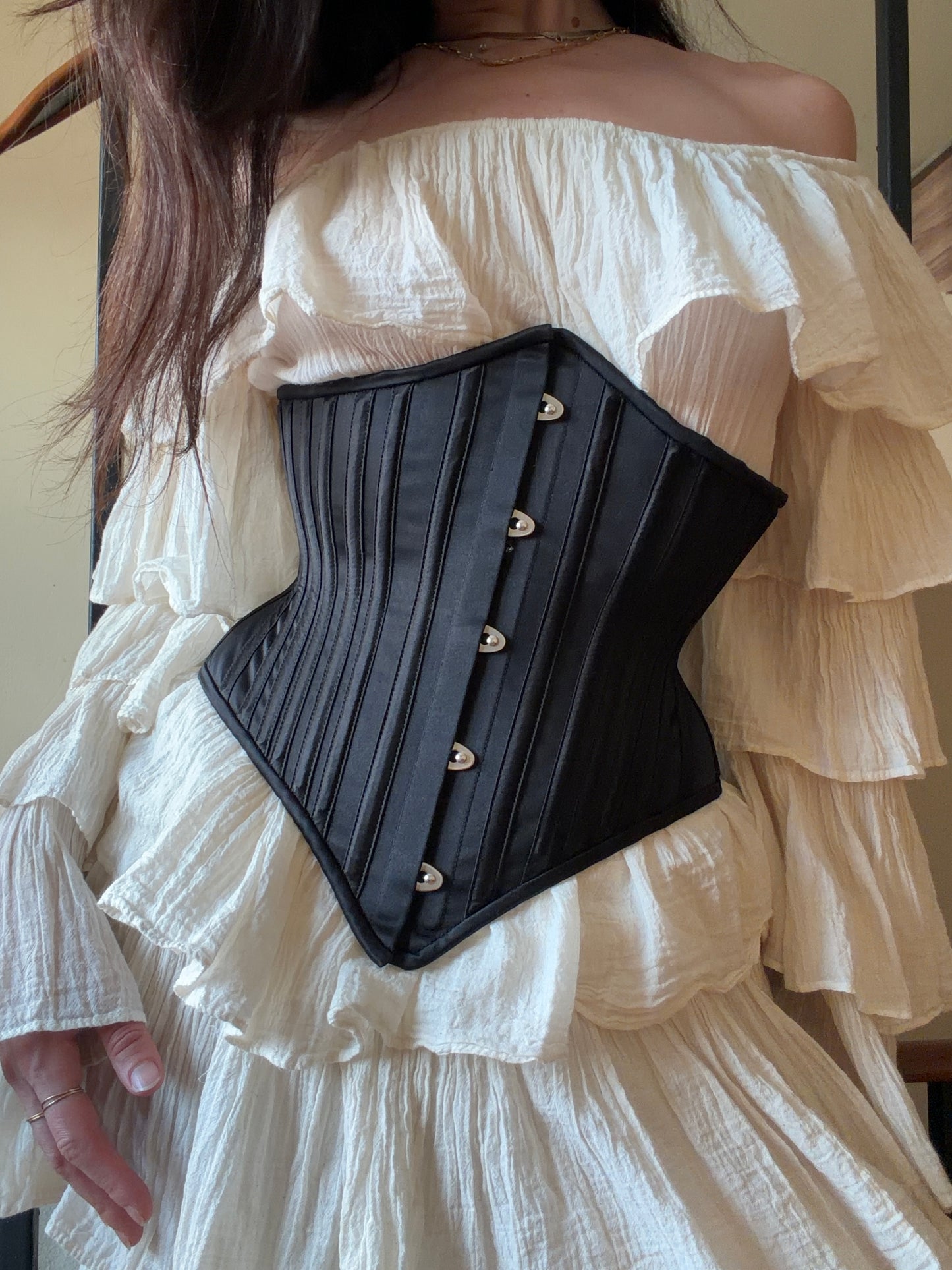 Black corset worn over a white off-shoulder dress.