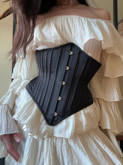 Black corset worn over a white off-shoulder dress.