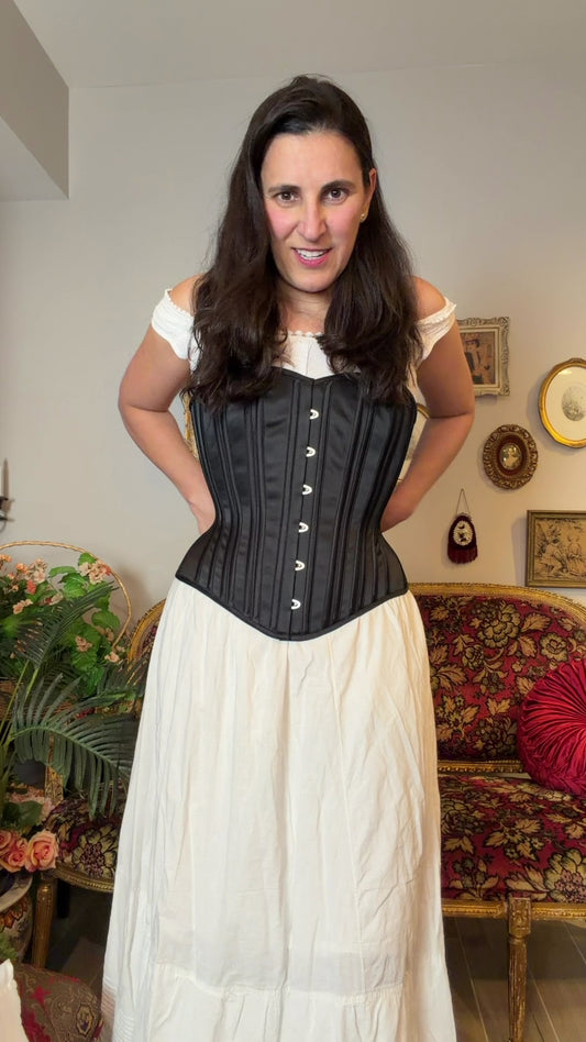 woman in a chemise putting on a corset